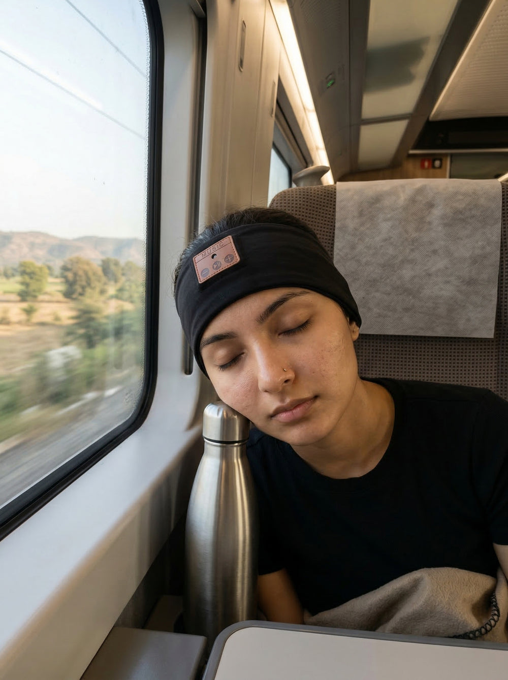 Person sleeping on a train with a scenic view outside the window