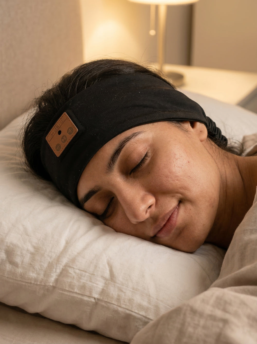 Person sleeping with a black sleep headband on a pillow and beatband
